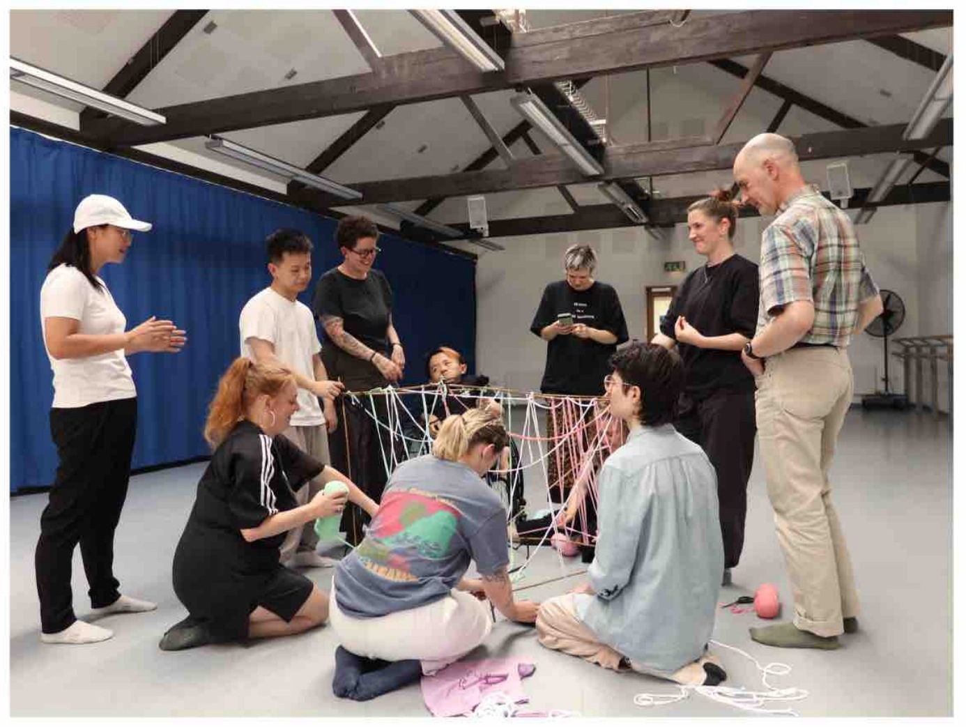 Artists gathered around a hanging thread structure
